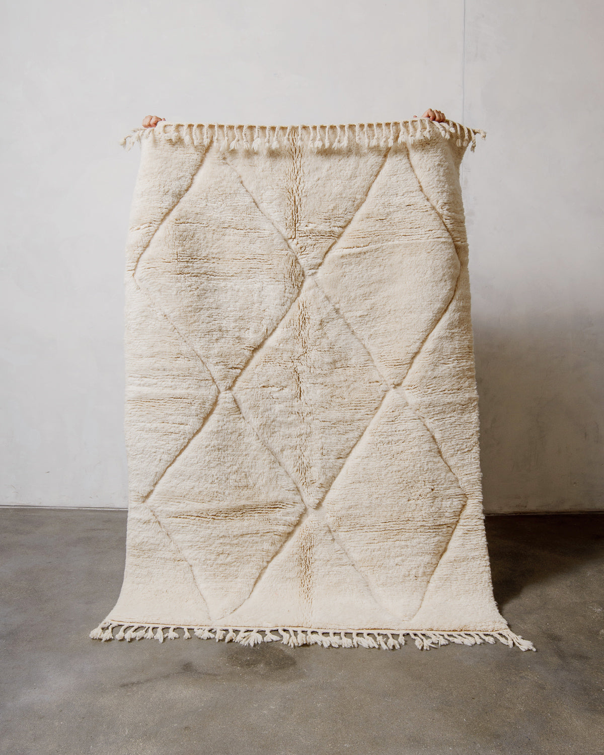 Cream wool rug with diamond pattern on a plain background